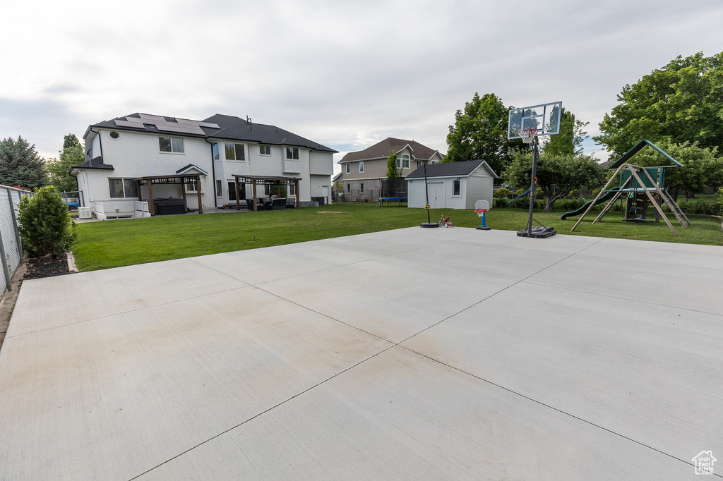 View of sport court featuring a playground and a storage unit