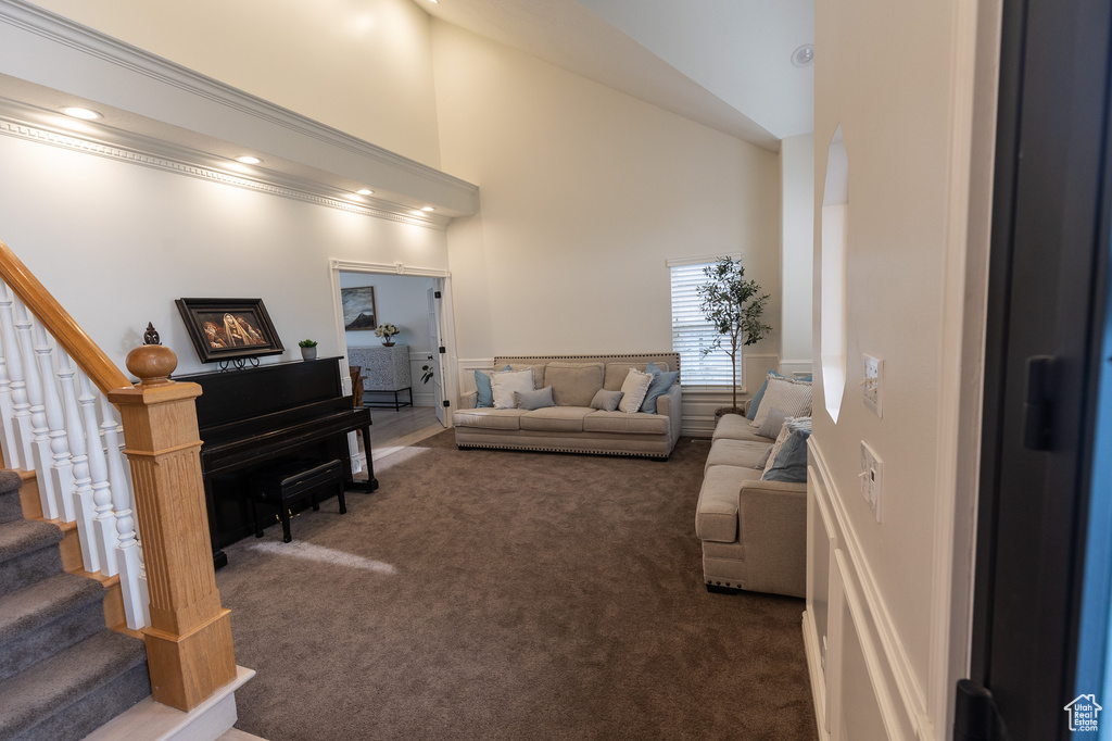 Living area featuring carpet, high vaulted ceiling, and stairs