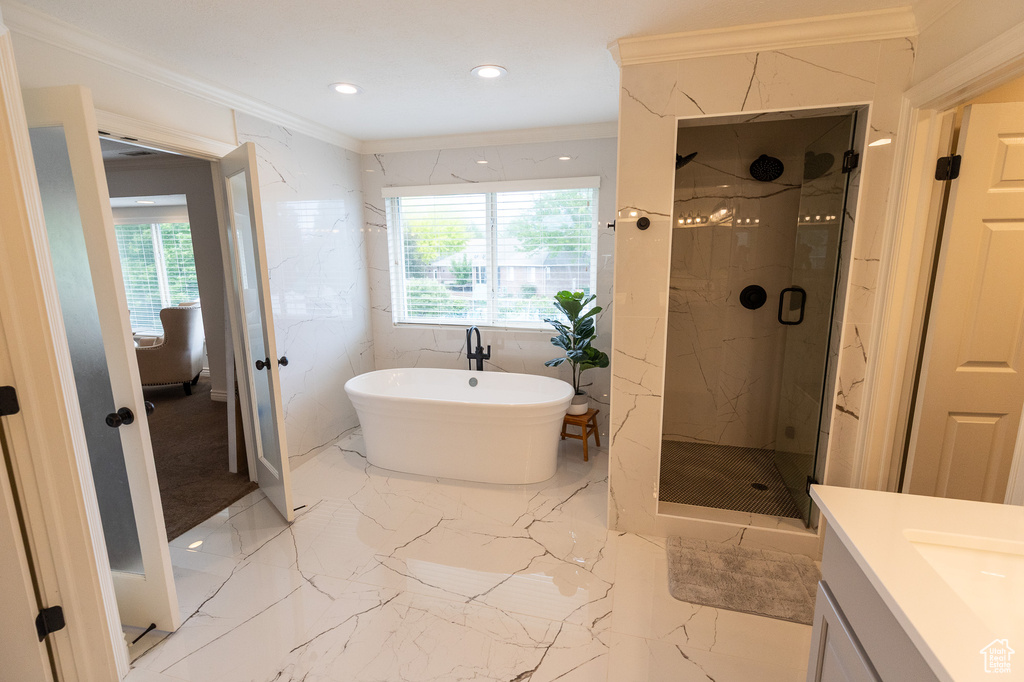 Bathroom featuring a marble finish shower, plenty of natural light, crown molding, a freestanding tub, and recessed lighting