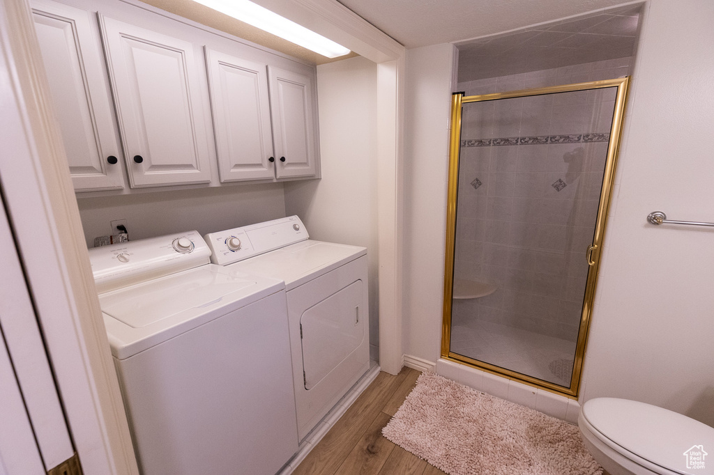 Laundry area with washing machine and clothes dryer, light wood-style flooring, cabinet space, and baseboards