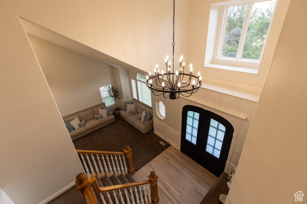 Foyer entrance featuring plenty of natural light, a high ceiling, a chandelier, french doors, and wood finished floors