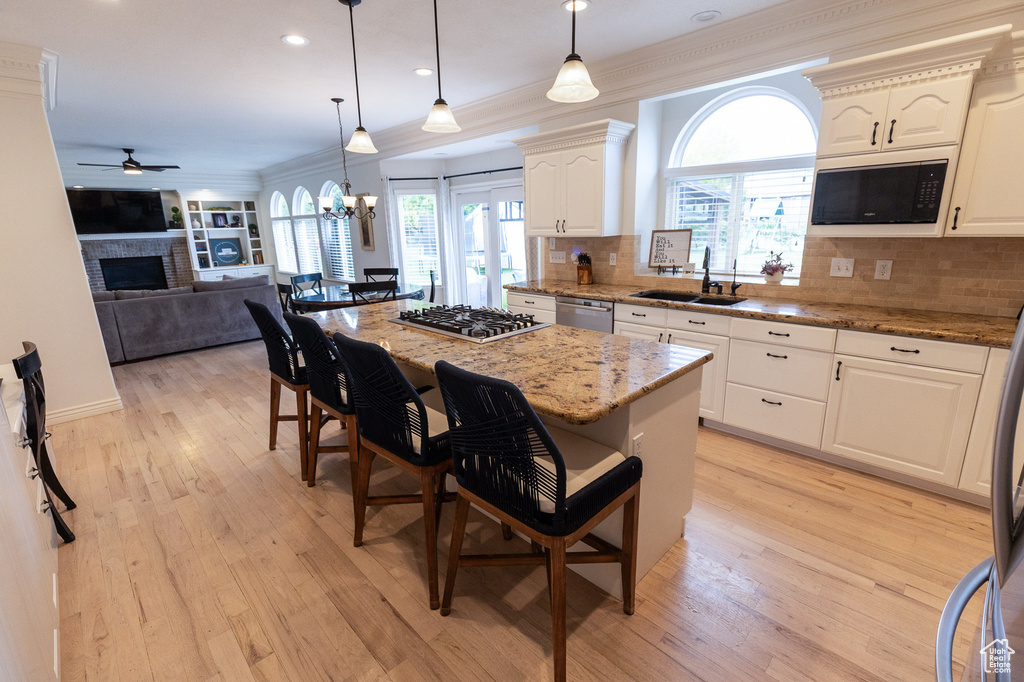 Kitchen featuring a sink, stainless steel appliances, a fireplace, a breakfast bar, and a ceiling fan