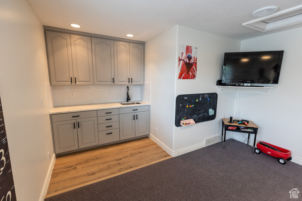 Indoor bar featuring baseboards, decorative backsplash, light wood-style floors, recessed lighting, and light colored carpet