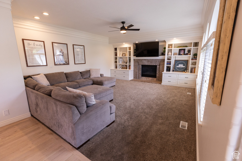 Living area with ceiling fan, a brick fireplace, crown molding, baseboards, and recessed lighting