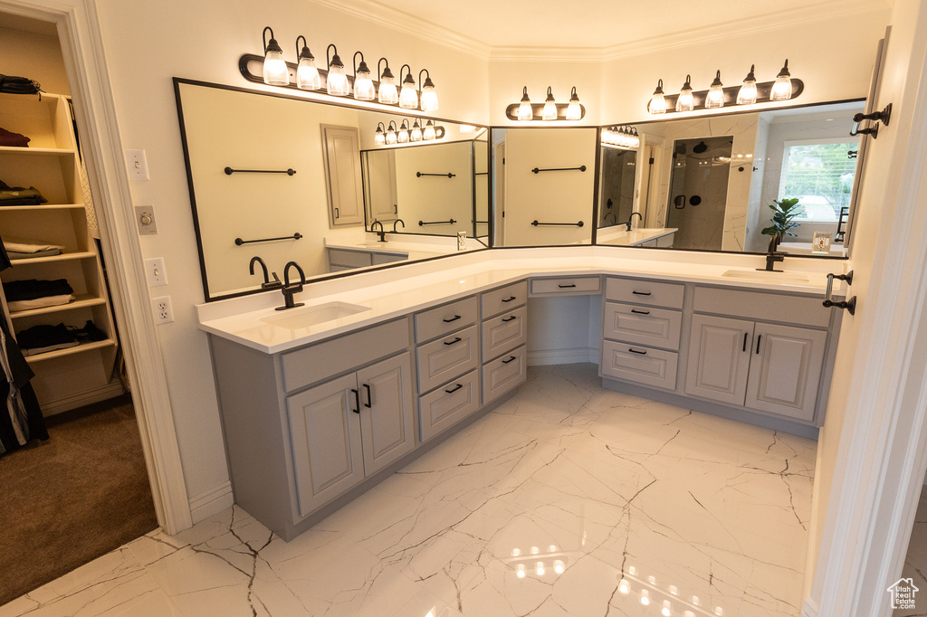 Full bath featuring a shower stall, a walk in closet, double vanity, ornamental molding, and marble finish floors
