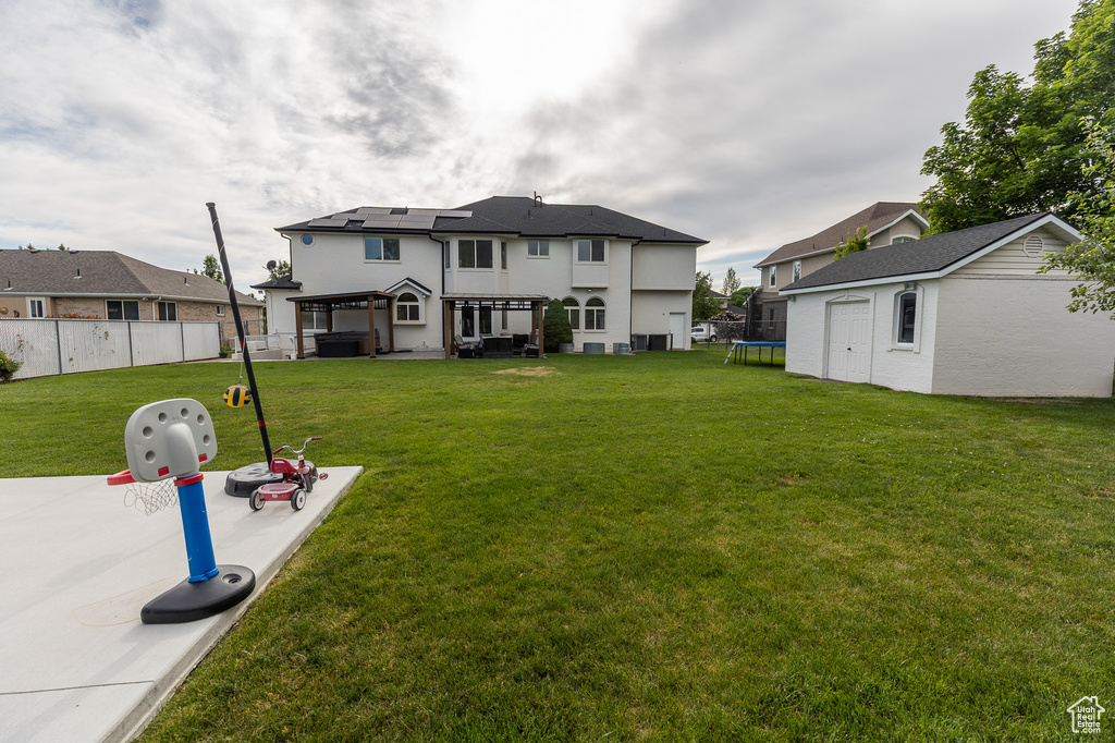 Back of property with a trampoline, an outbuilding, a patio, and stucco siding