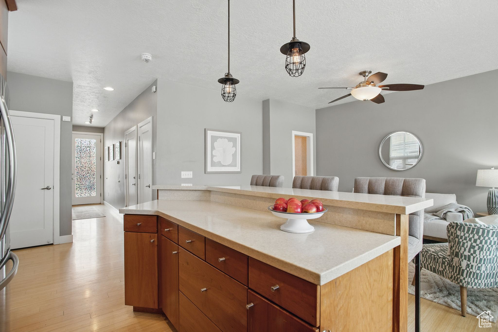 Kitchen featuring light wood-style flooring, open floor plan, light countertops, a kitchen bar, and a textured ceiling