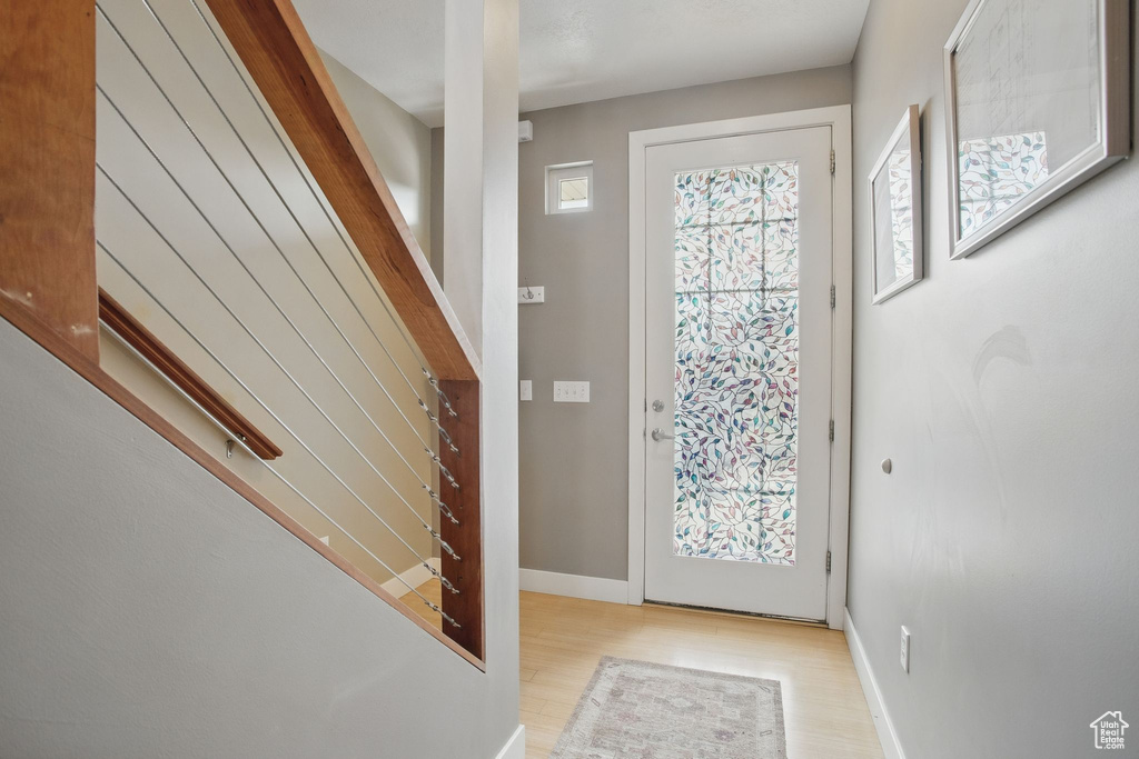 Foyer with light wood-style flooring, stairs, and baseboards