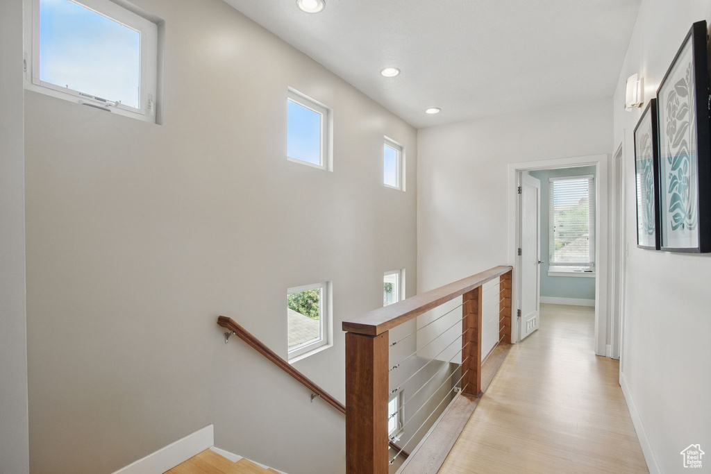 Hallway featuring an upstairs landing, plenty of natural light, baseboards, light wood-type flooring, and recessed lighting