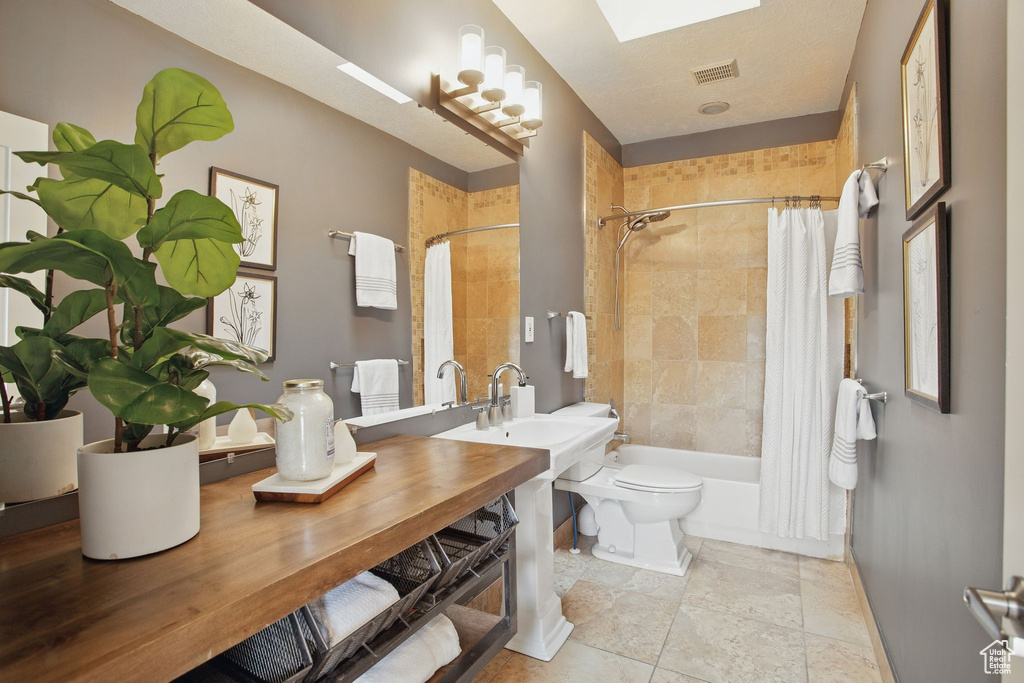 Full bath with baseboards, shower / tub combo, a sink, and toilet
