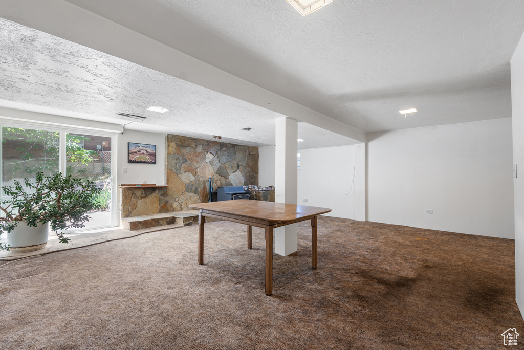 Playroom with carpet, a textured ceiling, and a wood stove