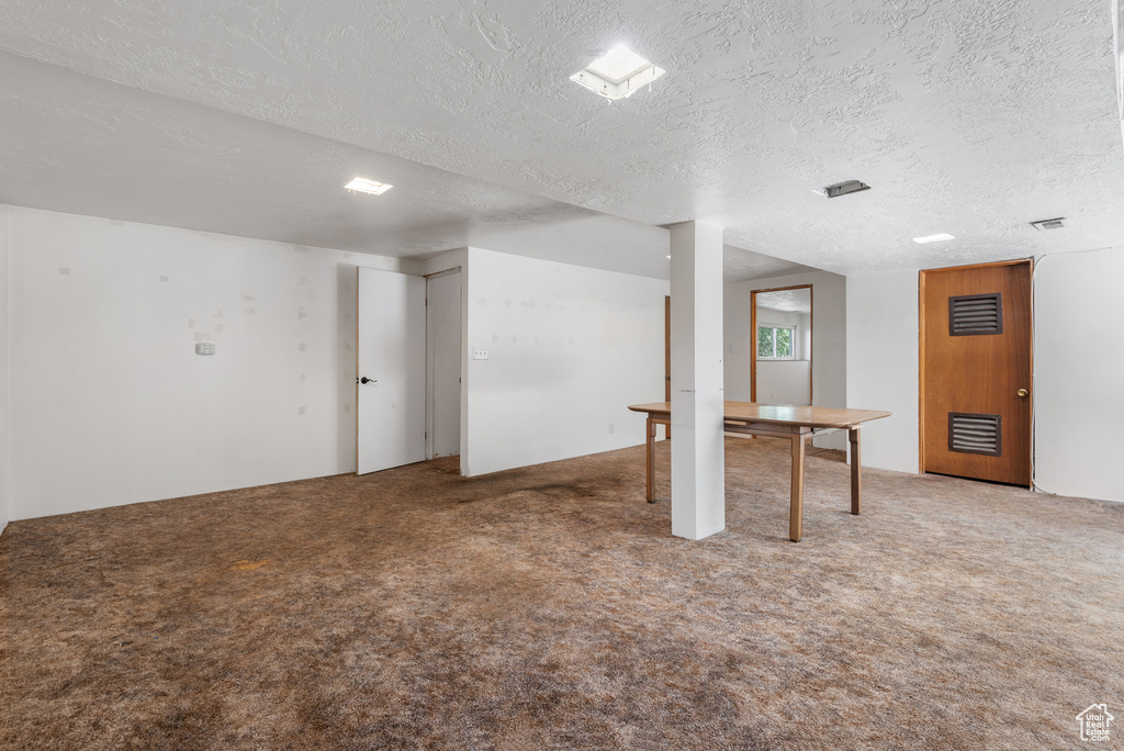 Finished below grade area featuring carpet floors and a textured ceiling