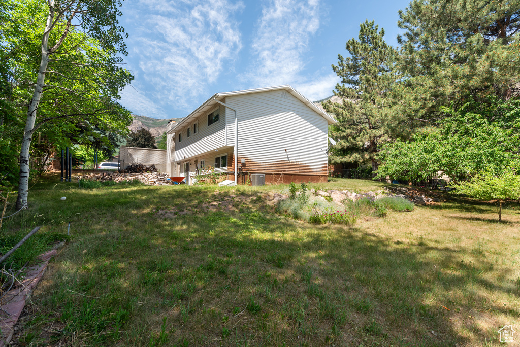 Back of house featuring a lawn and central air condition unit