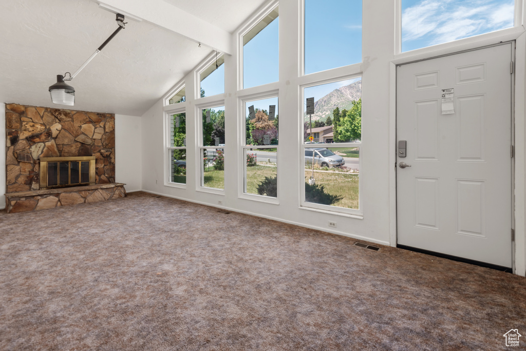 Unfurnished living room with plenty of natural light, carpet, a stone fireplace, high vaulted ceiling, and beamed ceiling