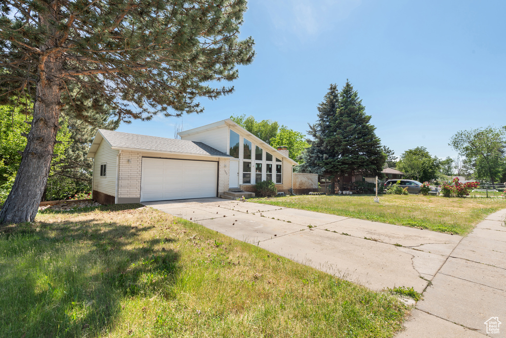 Mid-century inspired home featuring brick siding, a garage, a front yard, and concrete driveway