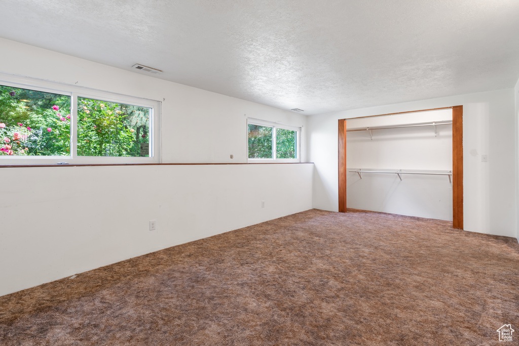 Unfurnished bedroom with carpet flooring, a textured ceiling, and a closet
