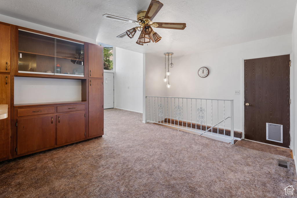 Spare room featuring carpet, a ceiling fan, and a textured ceiling
