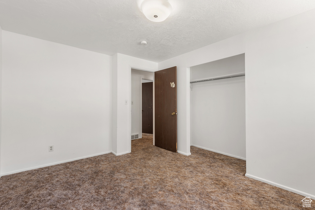 Unfurnished bedroom with carpet, a closet, baseboards, and a textured ceiling