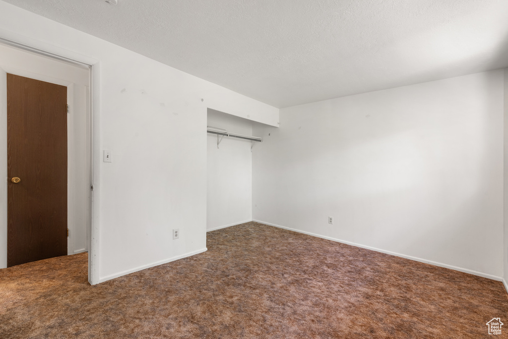 Unfurnished bedroom with carpet, a closet, and baseboards