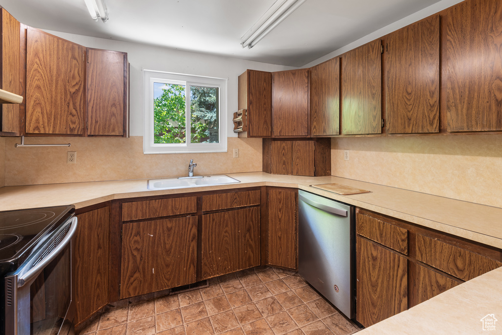 Kitchen with stainless steel appliances, a sink, backsplash, and light countertops