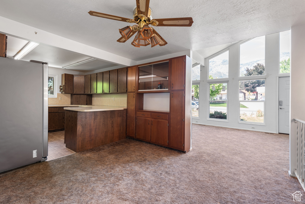 Kitchen with freestanding refrigerator, healthy amount of natural light, a peninsula, and ceiling fan