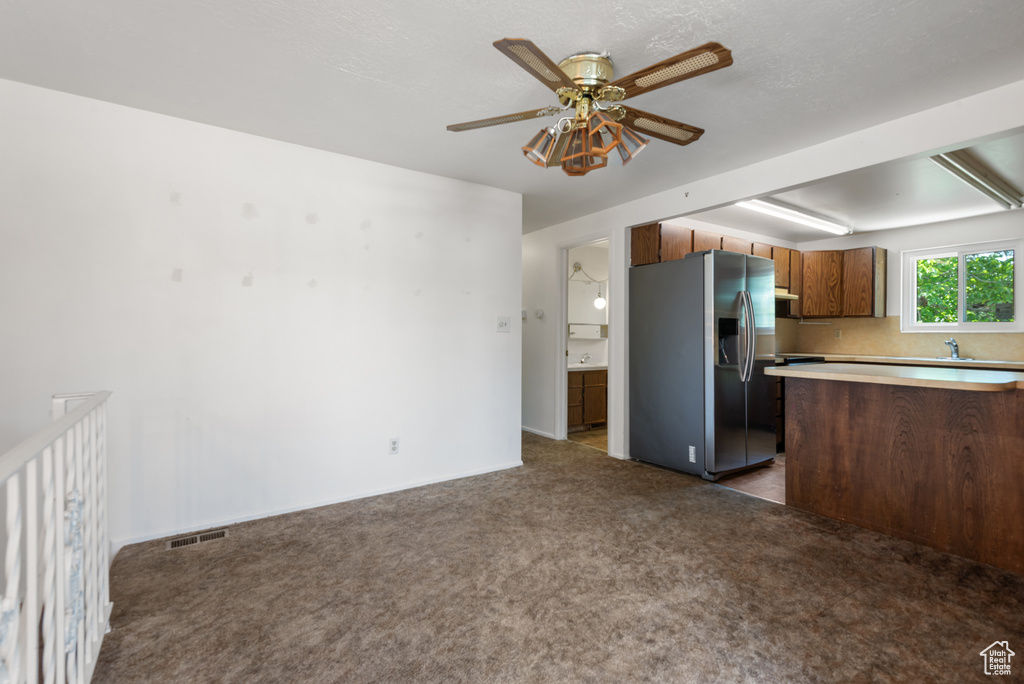 Kitchen with stainless steel refrigerator with ice dispenser, light countertops, carpet, ceiling fan, and a sink
