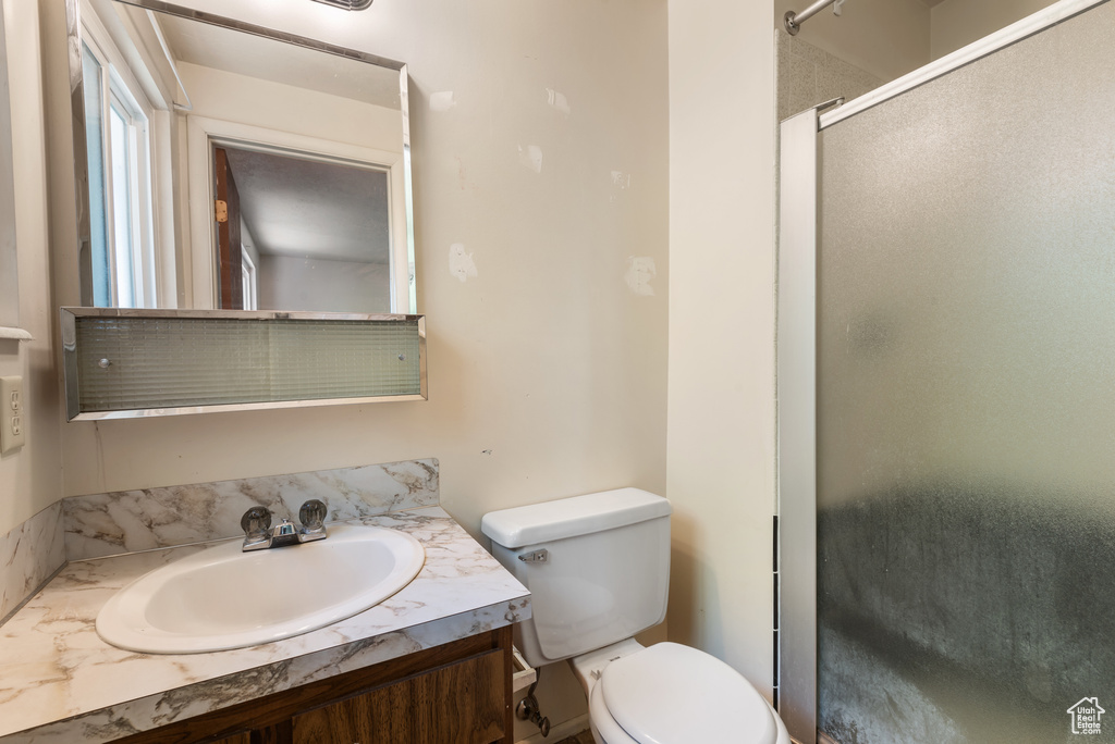 Full bath featuring toilet, vanity, and a shower with shower door