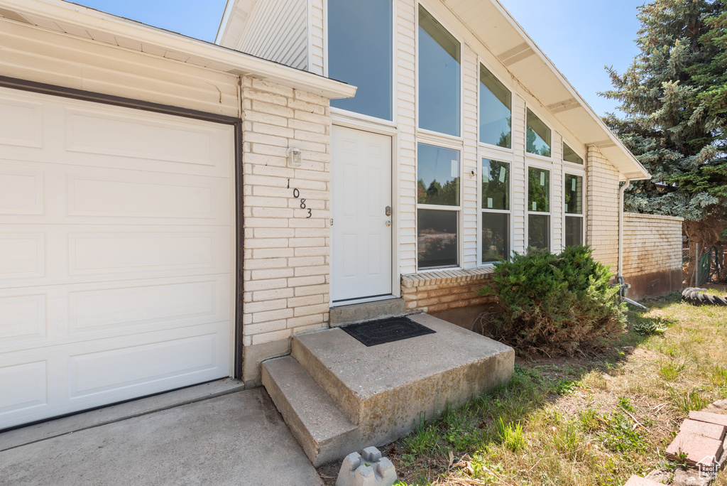 Doorway to property featuring a garage, brick siding, and a chimney