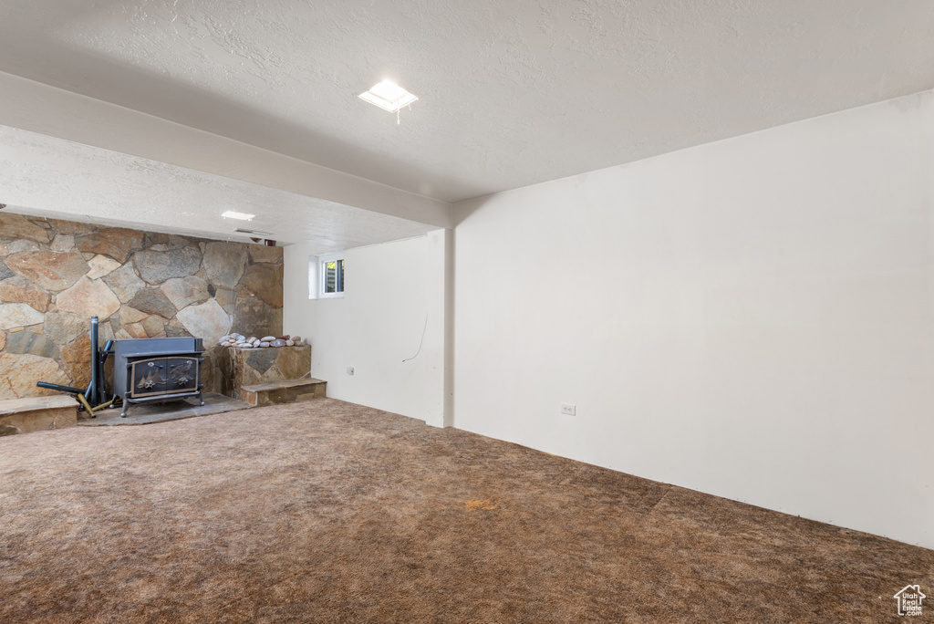 Living room with a wood stove, carpet floors, and a textured ceiling