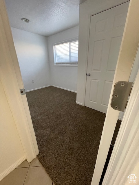 Unfurnished room with dark colored carpet, baseboards, and a textured ceiling