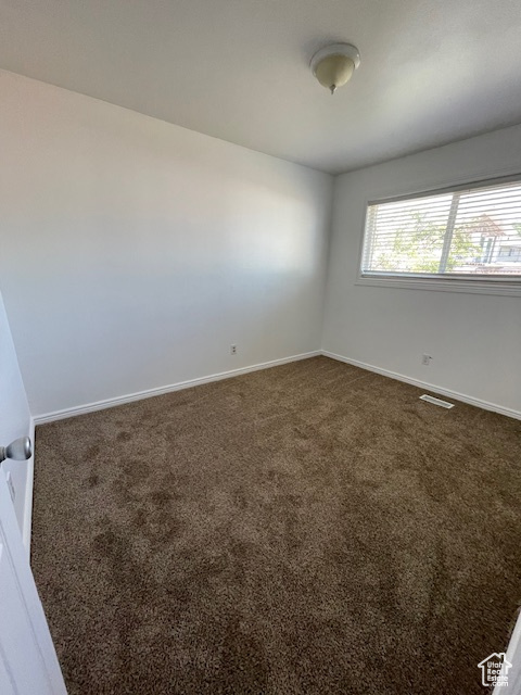 Spare room with dark colored carpet and baseboards