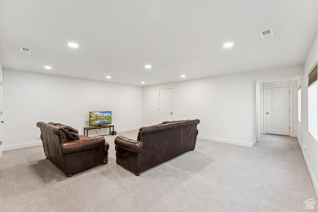Living area with light carpet, recessed lighting, and baseboards