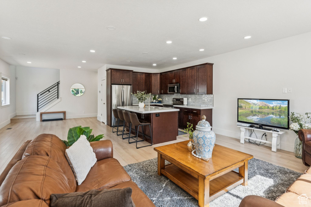Living area with light wood-type flooring, recessed lighting, and stairs