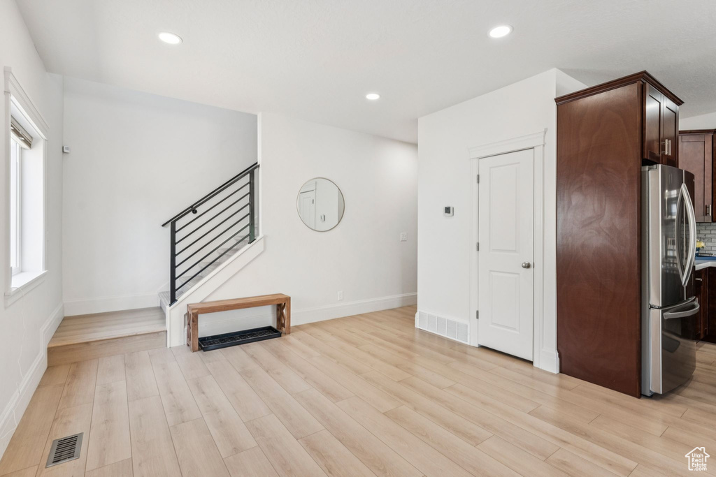 Unfurnished living room featuring stairway, light wood-style floors, baseboards, and recessed lighting
