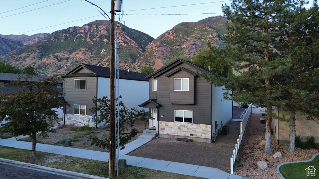 View of front of house with a mountain view, central AC unit, and stone siding