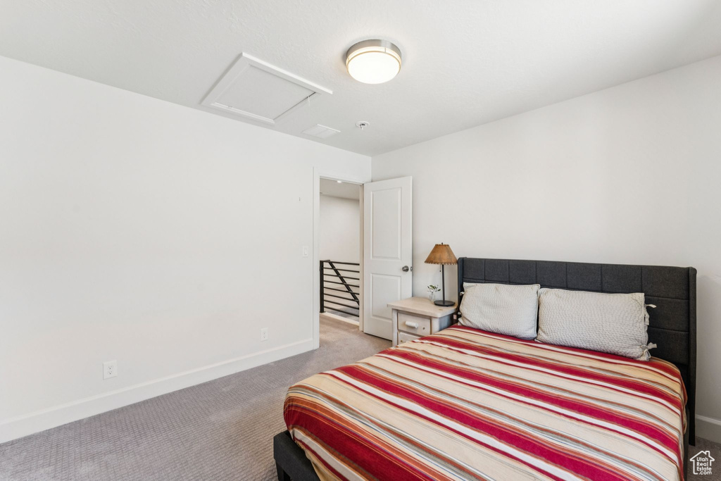 Carpeted bedroom featuring attic access and baseboards