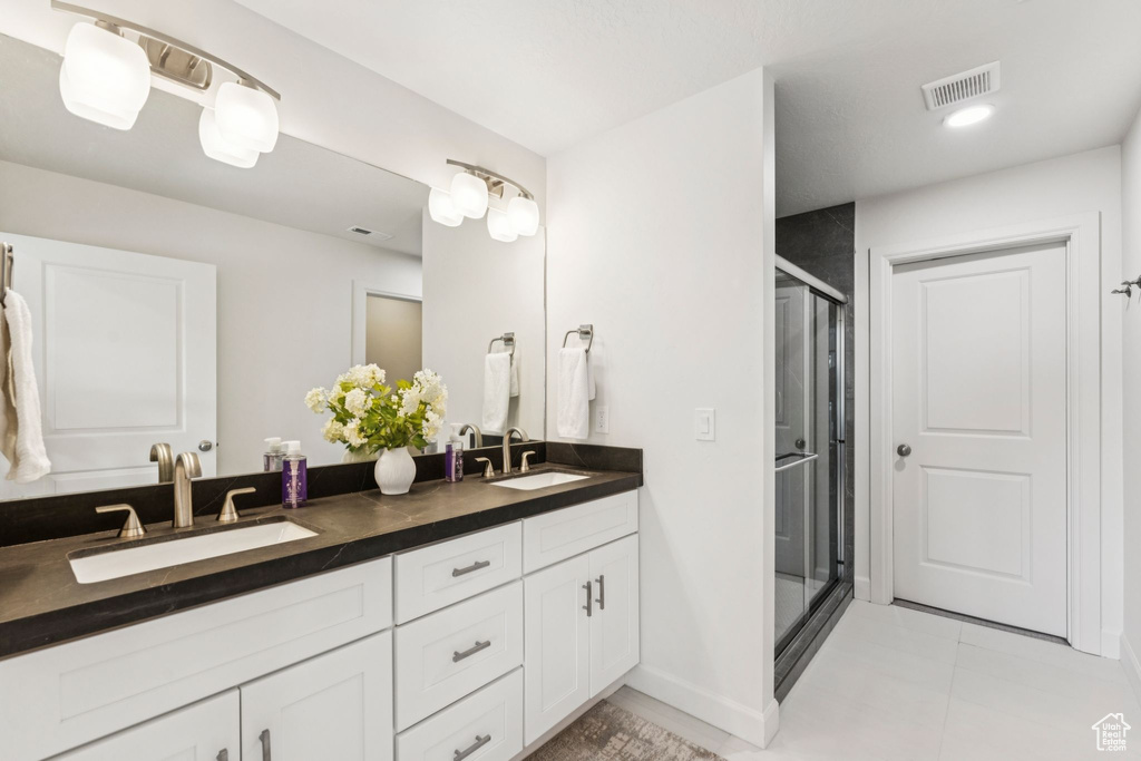 Bathroom featuring double vanity, a shower stall, tile patterned floors, and baseboards