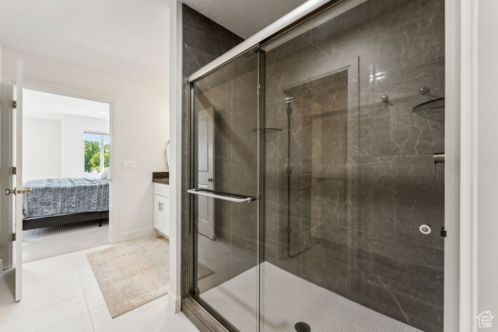 Bathroom with a stall shower, connected bathroom, tile patterned floors, and vanity