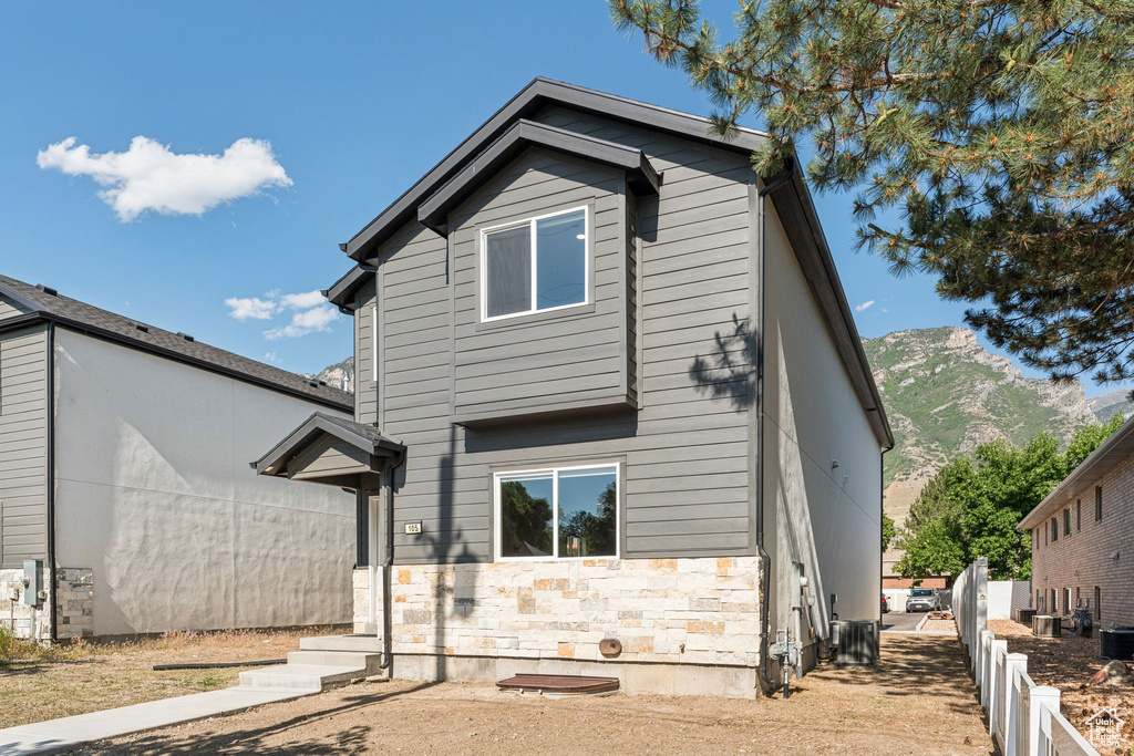 Rear view of property with stone siding, a mountain view, and central air condition unit
