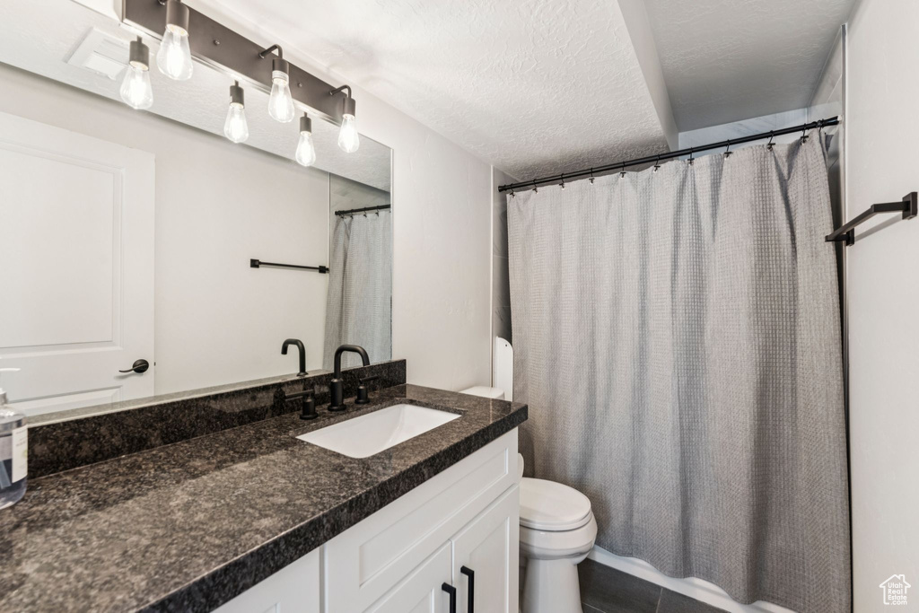 Bathroom with toilet, vanity, a textured ceiling, and tile patterned flooring