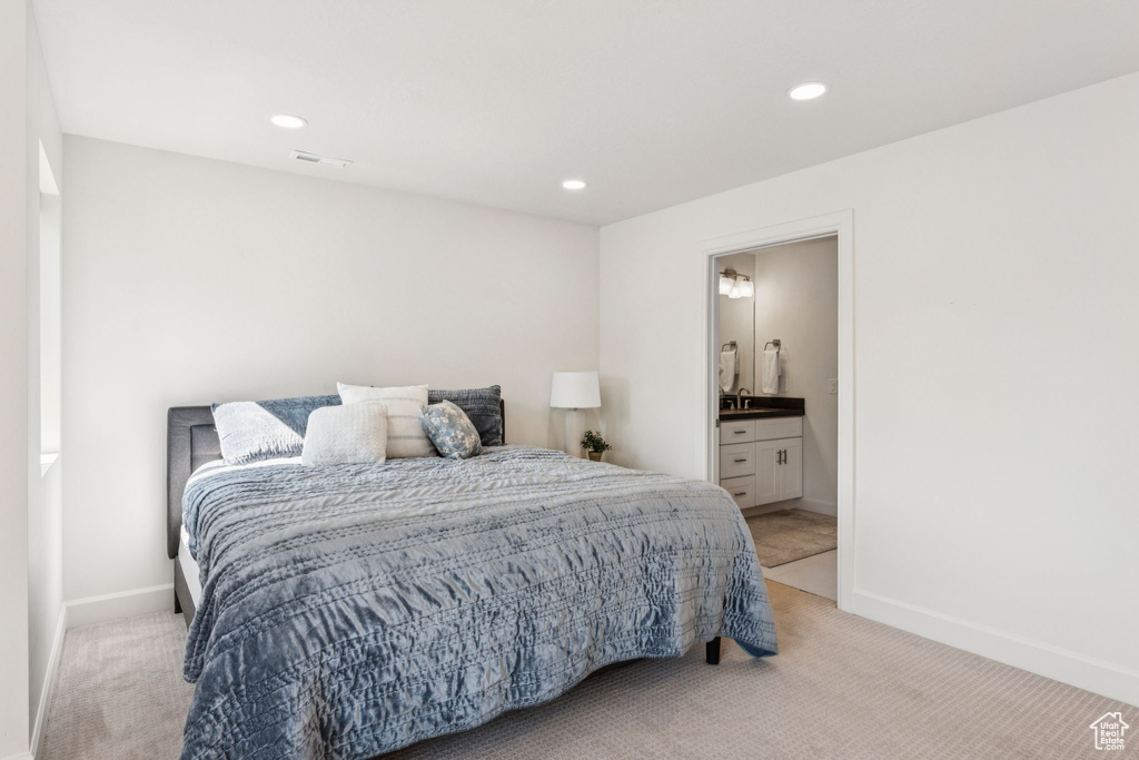Bedroom with light colored carpet, baseboards, recessed lighting, and ensuite bath