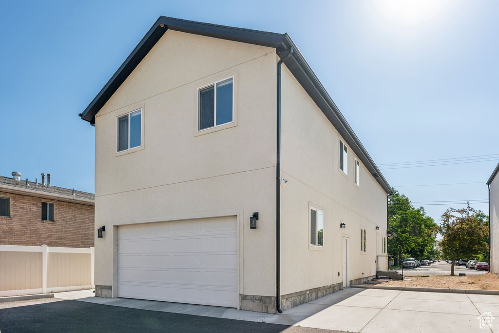 View of property exterior featuring an attached garage, stucco siding, and driveway