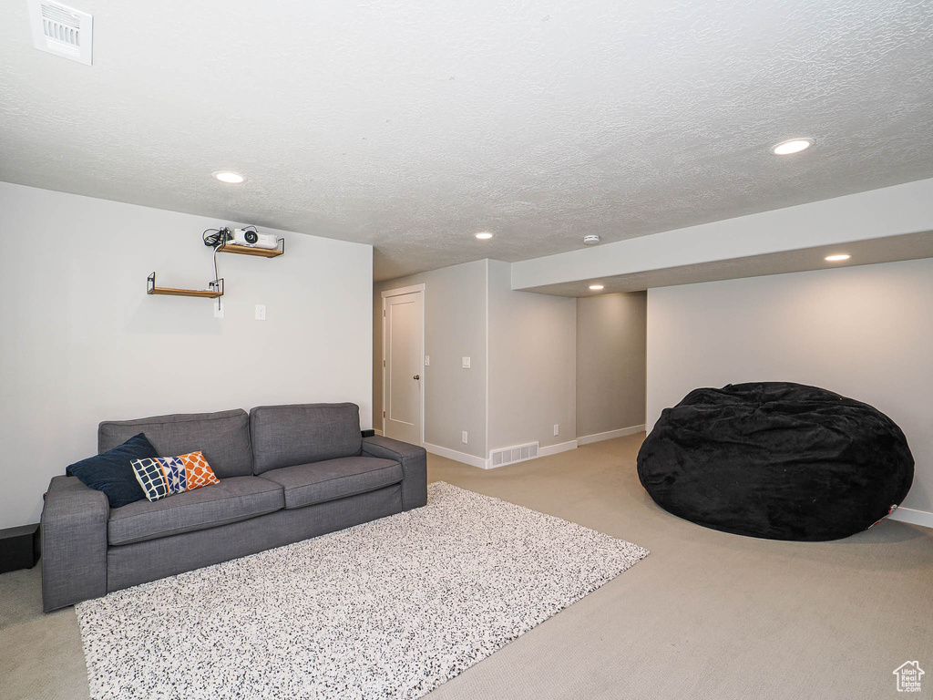 Living room with light colored carpet, recessed lighting, baseboards, and a textured ceiling