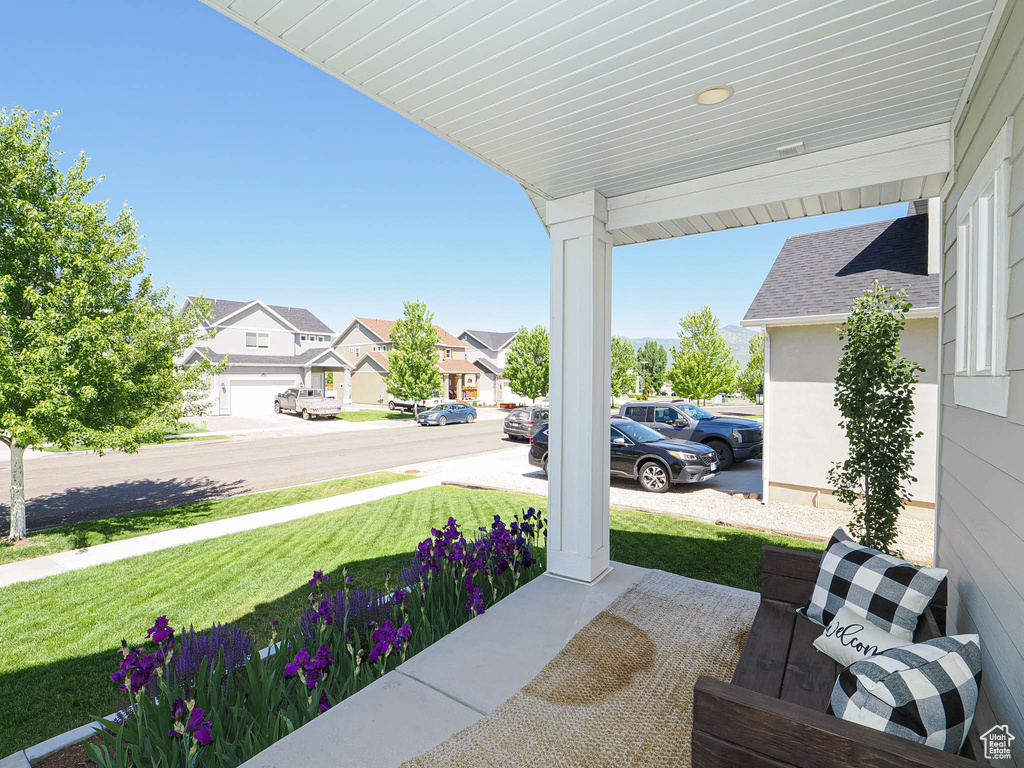 Covered porch featuring a residential view and a yard