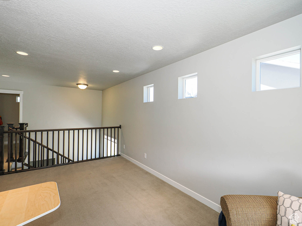 Empty room with light colored carpet, recessed lighting, baseboards, and a textured ceiling