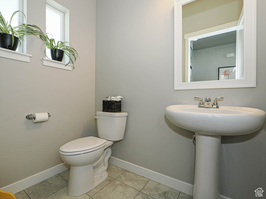 Bathroom featuring toilet, baseboards, and tile patterned floors