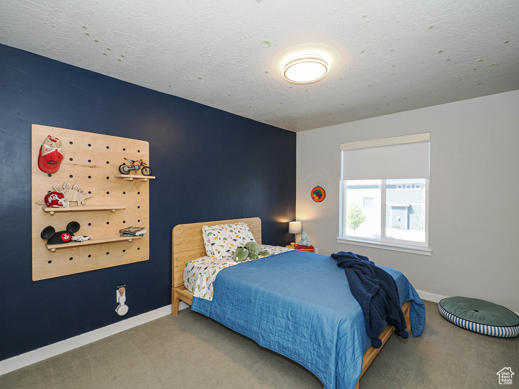 Bedroom featuring carpet flooring, baseboards, and a textured ceiling