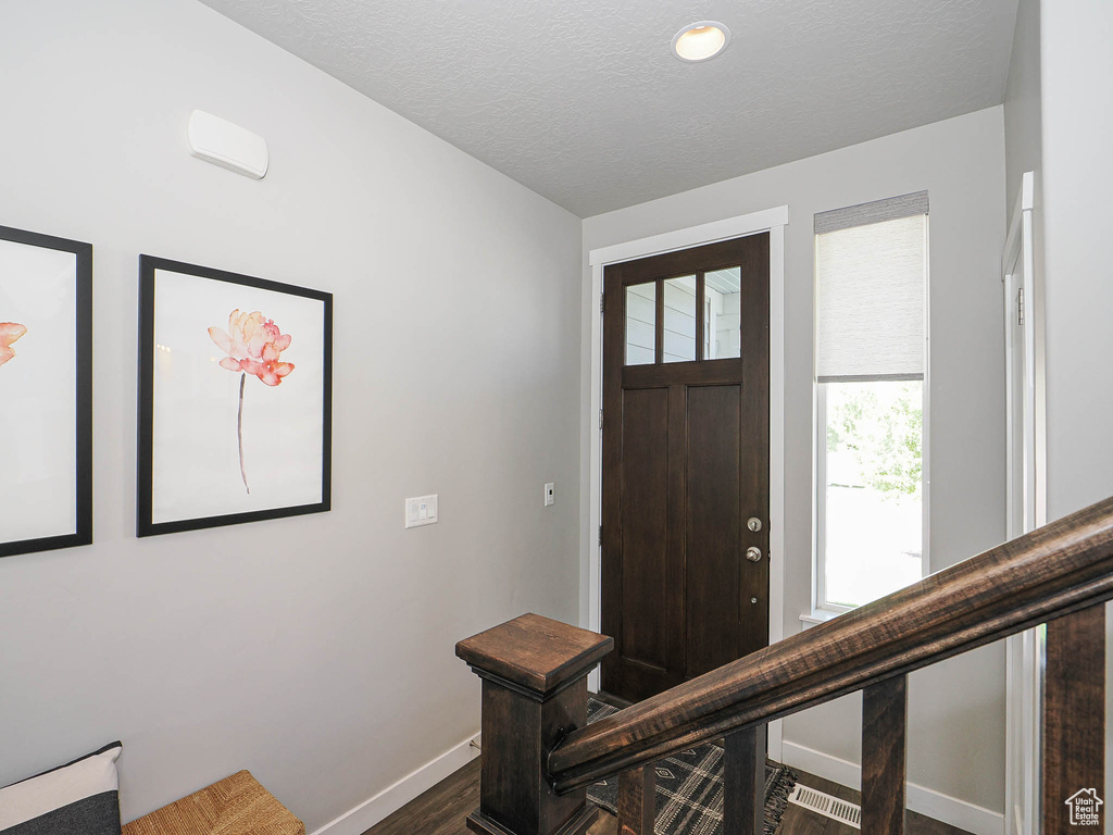 Entrance foyer with baseboards, dark wood-type flooring, and a textured ceiling