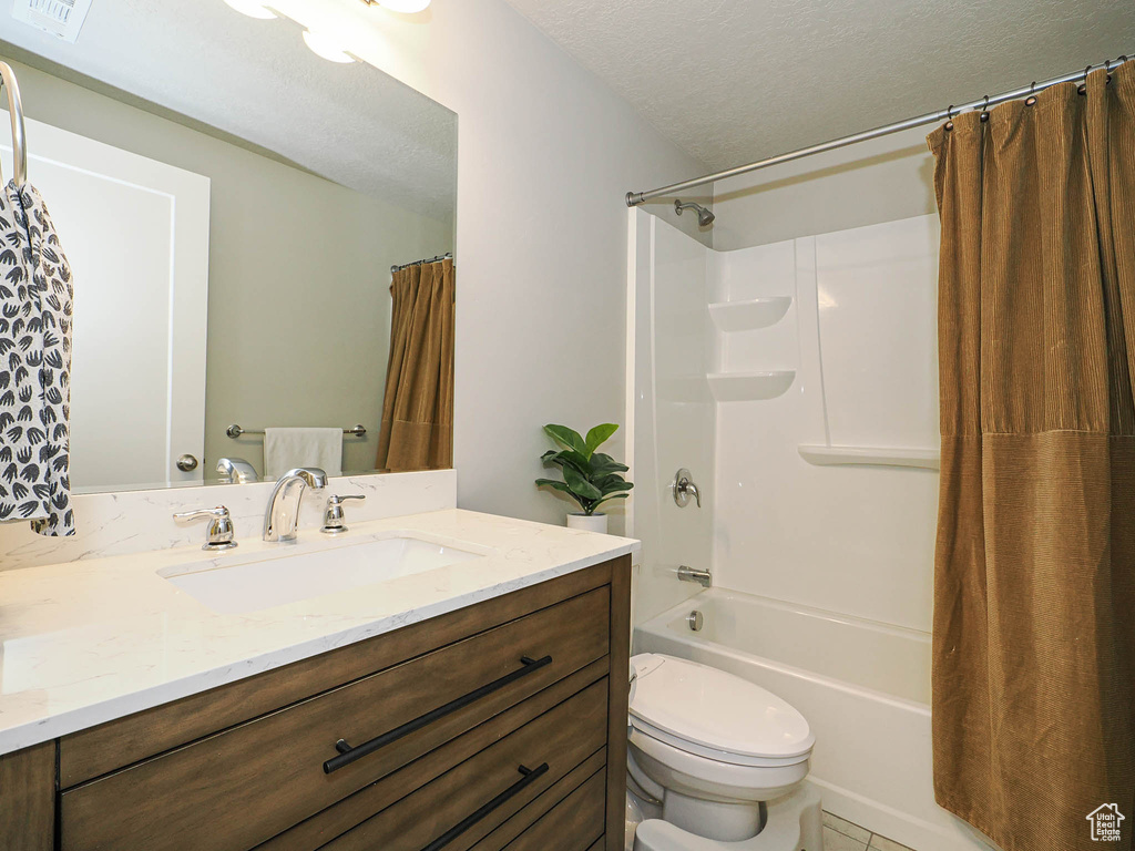 Bathroom with vanity, toilet, shower / bath combo with shower curtain, a textured ceiling, and tile patterned flooring