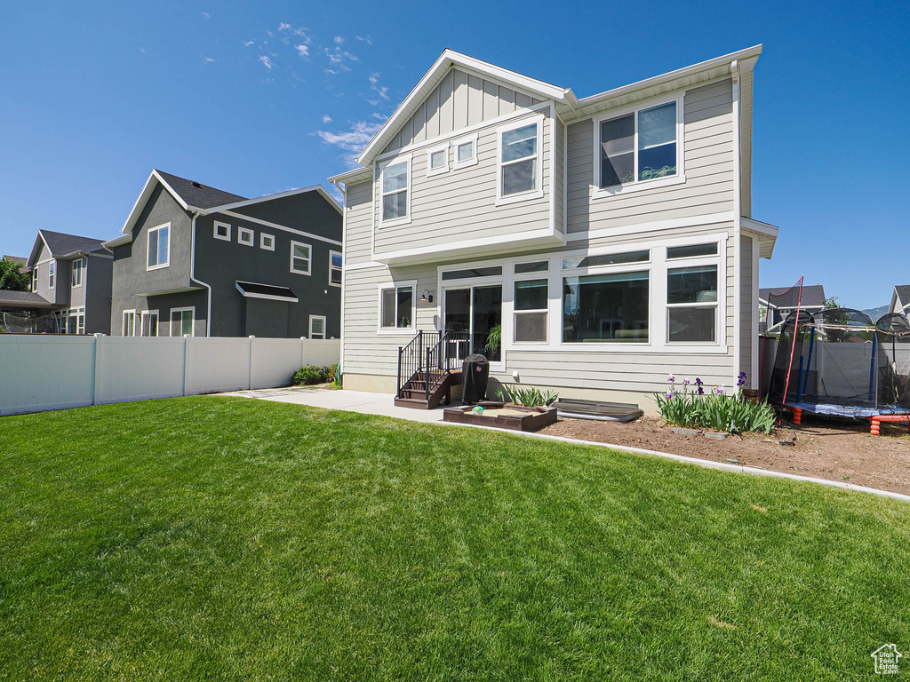 Back of property with a trampoline, board and batten siding, and a patio